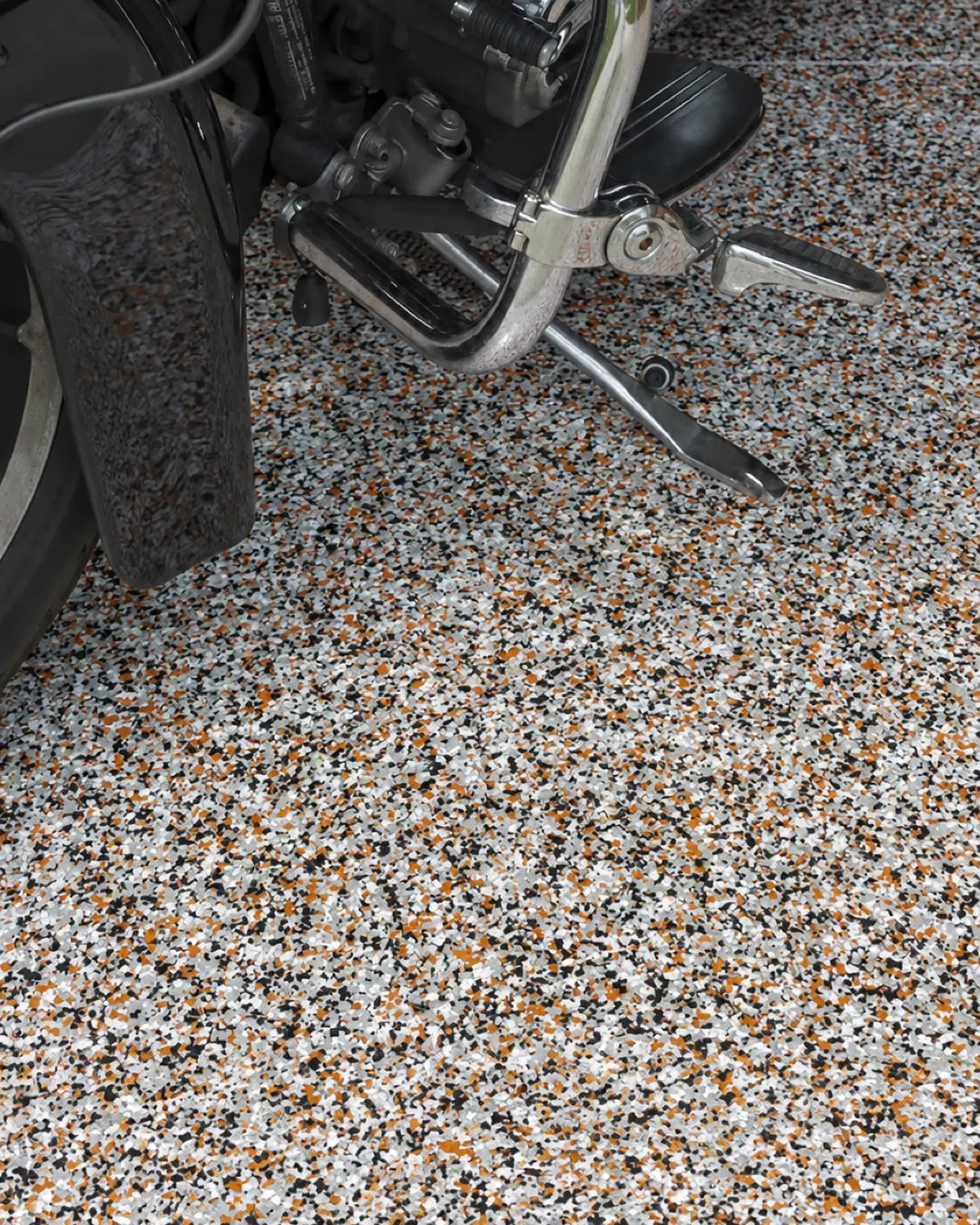 Piso epóxico de hojuela de tonos cálidos con motocicleta (imagen de referencia)